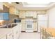 Well-lit kitchen with tile flooring, standard white appliances, and bright white cabinets at 12511 Dearborn Dr, Hudson, FL 34667