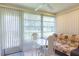 Light-filled sun room with large windows, vertical blinds, and a cozy seating area with a decorative couch at 12511 Dearborn Dr, Hudson, FL 34667