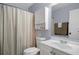 Well-lit bathroom showcasing a white vanity, toilet, and a shower with patterned curtain at 13923 Pathfinder Dr, Tampa, FL 33625
