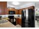 Functional kitchen featuring a black refrigerator, microwave, and dark wood cabinetry at 13923 Pathfinder Dr, Tampa, FL 33625