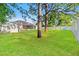 Expansive backyard featuring a well-maintained lawn, mature trees, white vinyl fence, and storage shed at 13935 Coronado Dr, Spring Hill, FL 34609
