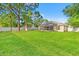 The spacious backyard features lush lawn, a screen porch, storage shed, and a white vinyl fence at 13935 Coronado Dr, Spring Hill, FL 34609