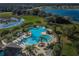 Gorgeous aerial view of the community pool, lush landscaping, and surrounding lake at 14008 Lugano Ct, Hudson, FL 34669