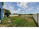 Expansive backyard features a white fence, lush green grass, a fire pit, and a tranquil water view at 14008 Lugano Ct, Hudson, FL 34669