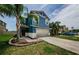 Two-story blue home featuring a large two-car garage, well-manicured lawn, and beautiful palm trees at 14008 Lugano Ct, Hudson, FL 34669