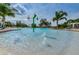 Beautiful community splash pool with beach entry, palm trees, and lounging chairs at 14008 Lugano Ct, Hudson, FL 34669