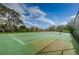 A well-maintained tennis court on a clear day, perfect for recreational play, surrounded by mature trees and landscaping at 14008 Lugano Ct, Hudson, FL 34669