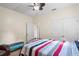 Bright bedroom featuring a ceiling fan, closet, and a bed with colorful striped bedding at 15613 Charmwood Dr, Hudson, FL 34667