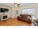 Bright and spacious living room featuring hardwood floors, a ceiling fan, and a cozy electric fireplace at 15613 Charmwood Dr, Hudson, FL 34667