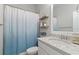 Bright bathroom featuring a vanity with stone countertop and decorative shelving with a blue ombre shower curtain at 16697 Courtyard Loop, Land O Lakes, FL 34638