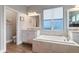 Bright bathroom featuring a soaking tub, dual vanities, tile flooring, and a separate toilet room at 16697 Courtyard Loop, Land O Lakes, FL 34638