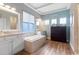 Bright bathroom featuring a soaking tub, three windows, and hardwood floors at 16697 Courtyard Loop, Land O Lakes, FL 34638