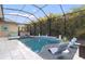 Screened-in pool with luxurious lounge chairs and hot tub surrounded by lush landscaping at 16697 Courtyard Loop, Land O Lakes, FL 34638