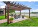 Enjoy outdoor living with a pergola-covered patio overlooking a serene lake and manicured lawn at 1760 Fox Grape Loop, Lutz, FL 33558