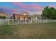 Large fenced backyard at dusk, showcasing a fire pit, patio with pergola, and inviting outdoor lighting at 1760 Fox Grape Loop, Lutz, FL 33558