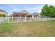 Spacious backyard with a pergola-covered patio, fire pit, and a well-maintained white picket fence at 1760 Fox Grape Loop, Lutz, FL 33558