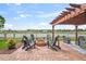 Relaxing backyard patio with a pergola, a brick firepit, views of the lake, and comfortable outdoor seating at 1760 Fox Grape Loop, Lutz, FL 33558