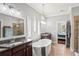 Bright bathroom with double sinks, a luxurious soaking tub, walk-in shower with glass door and access to the main bedroom at 1760 Fox Grape Loop, Lutz, FL 33558