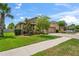 Charming exterior view of a well-maintained home with lush green lawn, mature trees, and a paved driveway at 1760 Fox Grape Loop, Lutz, FL 33558
