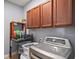 Functional laundry room with modern washer and dryer, upper cabinets, and a convenient storage shelf at 1760 Fox Grape Loop, Lutz, FL 33558