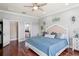 Bright main bedroom featuring wood floors, a ceiling fan, and a walk-in closet that leads to the primary bathroom at 1760 Fox Grape Loop, Lutz, FL 33558