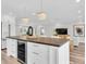 Open-concept kitchen island with a wooden countertop, a wine cooler, and modern chandelier lighting at 18102 Spencer Rd, Odessa, FL 33556