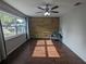Bright living room featuring hardwood floors, a wood accent wall, a ceiling fan, and a large window at 2004 Culberson Ave, Dunedin, FL 34698