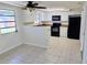 Well-lit kitchen featuring white cabinets, black appliances, and tile floors at 2051 Peggy Dr, Holiday, FL 34690