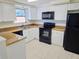 Kitchen features white cabinets, tile floors, black appliances, and granite countertops, providing a functional workspace at 2051 Peggy Dr, Holiday, FL 34690