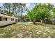 Expansive backyard featuring a refreshing pool, mature trees, and the home's screened lanai at 22154 Weeks Blvd, Land O Lakes, FL 34639
