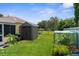 Green backyard features a shed and greenhouse, offering a serene outdoor space at 2585 Waterfall Dr, Spring Hill, FL 34608