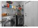 Well-equipped laundry room features modern washer and dryer, shelving, and convenient access door at 2585 Waterfall Dr, Spring Hill, FL 34608