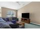 Bright living room featuring a cozy couch, wooden center table, vaulted ceiling, and a large sunny window at 2585 Waterfall Dr, Spring Hill, FL 34608