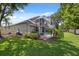 The exterior of the home shows a screened lanai and spacious yard with lush green grass and landscaping at 3243 Stonegate Falls Dr, Land O Lakes, FL 34638