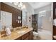 Well lit bathroom with granite countertop, chocolate colored wall, and shower-tub combo at 3243 Stonegate Falls Dr, Land O Lakes, FL 34638