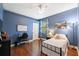 This bedroom is painted blue, and features hardwood floors, a ceiling fan, and a bedside lamp at 3243 Stonegate Falls Dr, Land O Lakes, FL 34638