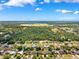 Wide aerial view of a residential neighborhood surrounded by lush greenery and blue skies at 3468 El Prado Ave, Spring Hill, FL 34609
