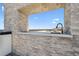 Modern outdoor kitchen featuring a stone backsplash and a sleek faucet overlooking the ocean at 4333 Harborpointe Dr, Port Richey, FL 34668