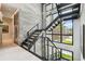 Modern staircase with a stone accent wall, pendant lights, and large windows overlooking a green lawn at 4333 Harborpointe Dr, Port Richey, FL 34668