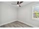 Bright bedroom with wood-look floors, ceiling fan, a window letting in natural light, and white walls at 4482 Kingston Dr, Hernando Beach, FL 34607