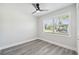 Bedroom with wood-look floors, ceiling fan, a window letting in natural light, and white walls at 4482 Kingston Dr, Hernando Beach, FL 34607