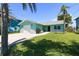 Charming aqua home with a paver driveway, complemented by lush green lawn and landscaping at 4482 Kingston Dr, Hernando Beach, FL 34607
