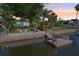 Waterfront home with a private dock and boat lift, featuring tropical landscaping and a charming backyard patio with chairs at 4942 Blue Heron Dr, New Port Richey, FL 34652