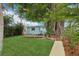 Lush backyard featuring a charming cottage, wooden deck, and beautiful mature trees at 4942 Blue Heron Dr, New Port Richey, FL 34652