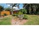 Landscaped backyard with a rock garden, various bushes, flowers, and mature trees at 5309 Bayonne Ave, Spring Hill, FL 34608