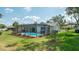Landscaped backyard with screened-in pool, lush green lawn, and well-maintained garden beds at 5309 Bayonne Ave, Spring Hill, FL 34608