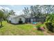 Landscaped backyard with screened-in pool, lush green lawn, and well-maintained garden beds at 5309 Bayonne Ave, Spring Hill, FL 34608