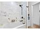 Modern bathroom featuring a soaking tub with a black showerhead and sleek white and gray marble tiles at 5340 Pilots Pl, New Port Richey, FL 34652
