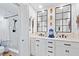 Bright bathroom with double sinks, white cabinetry, and a tiled shower with a glass door at 5340 Pilots Pl, New Port Richey, FL 34652