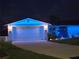 Charming home with a two-car garage and festive blue lighting outlining the roof and entry at night at 5340 Pilots Pl, New Port Richey, FL 34652